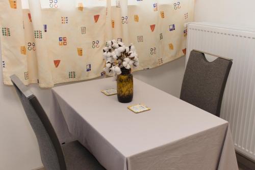 a white table with a vase of flowers on it at Silver Dream Apartmanház in Debrecen