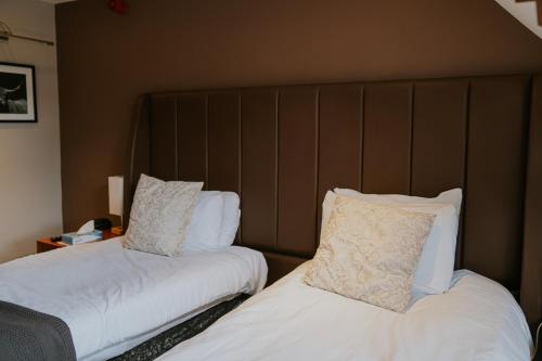 two beds in a hotel room with white sheets and pillows at Redesdale Arms Hotel in Moreton in Marsh