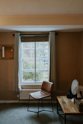 a room with a chair and a window and a table at Redesdale Arms Hotel in Moreton in Marsh