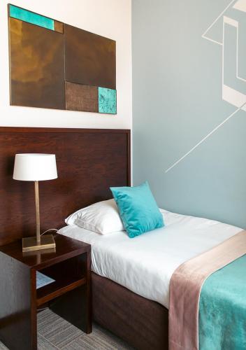 a bedroom with a bed and a table with a lamp at Europeum Hotel in Wrocław