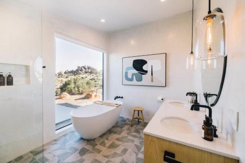 a white bathroom with a tub and a sink at Moonlight Mile By The Cohost Company in Pioneertown