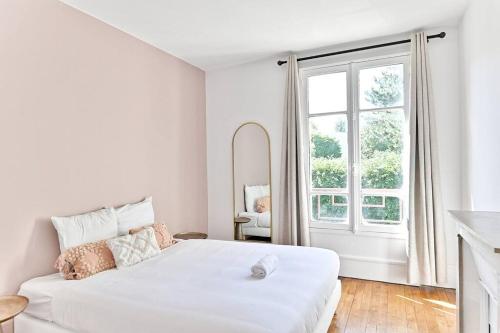 une chambre blanche avec un grand lit blanc et une fenêtre dans l'établissement Appartement lumineux Banlieue Parisienne - III, à Puteaux