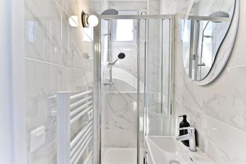une salle de bain avec une douche, un lavabo et un miroir dans l'établissement Appartement lumineux Banlieue Parisienne - III, à Puteaux