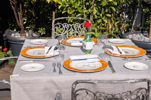 a table with plates and silverware and a red rose on top at Hotel Mecenate Palace in Rome