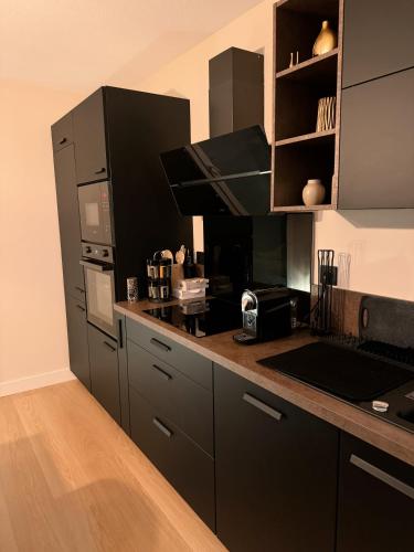 une cuisine avec des armoires noires et un comptoir dans l'établissement Appartement en résidence - PAU, à Pau