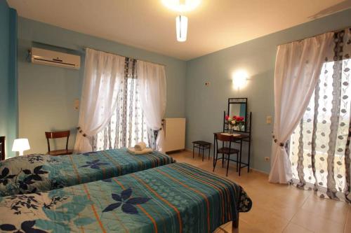 a bedroom with a bed and a table and two windows at Villa Christine - Maisonettes with fireplace in Aliveri