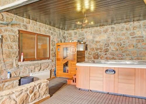 a stone bathroom with a tub and a sink at La Pedriza LA CASA DEL GALAPAGAR in Galapagar