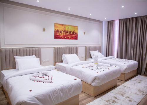 a hotel room with three beds with white sheets at Radiant Pyramids View in Cairo