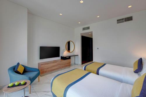 a hotel room with two beds and a television at SUHA Mina Rashid Hotel Apartments in Dubai