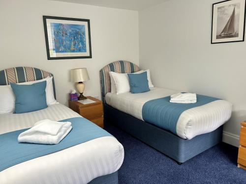 a room with two beds with blue and white pillows at Royal Ocean Racing Club in West Cowes