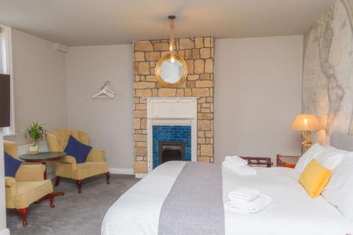 a bedroom with a large white bed and a fireplace at The Captain Cook in London