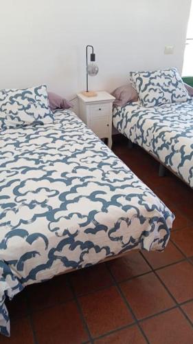 a bedroom with two beds and a table with a lamp at famarabeach2 in Famara