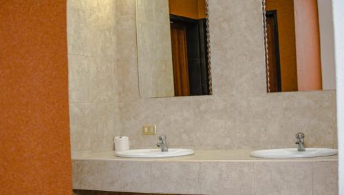 two sinks in a bathroom with two mirrors at Hotel Espor CA in Barinas