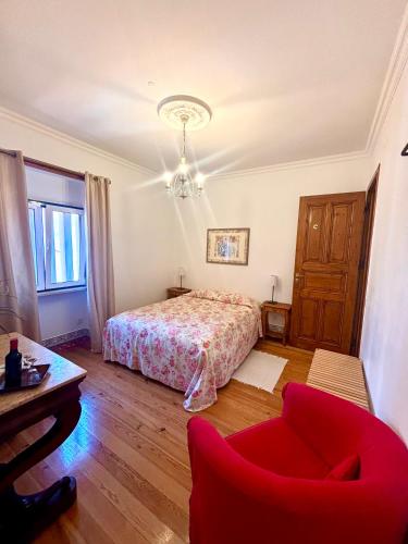 a bedroom with a bed and a red chair at Casa da Villa 1C in Sintra