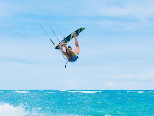 a man flying through the air while kiteboarding over the ocean at Kalpitiya Chalets by Thilanka in Kalpitiya