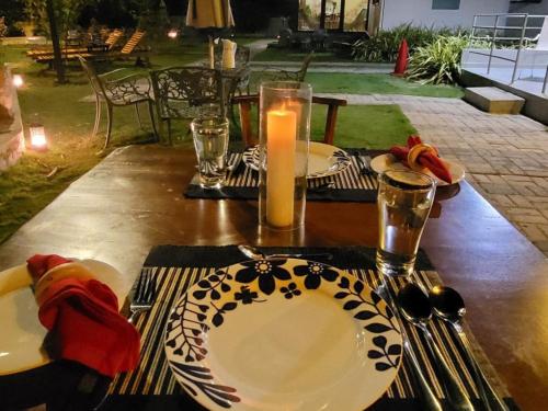 a wooden table with plates and a candle on it at Kalpitiya Chalets by Thilanka in Kalpitiya