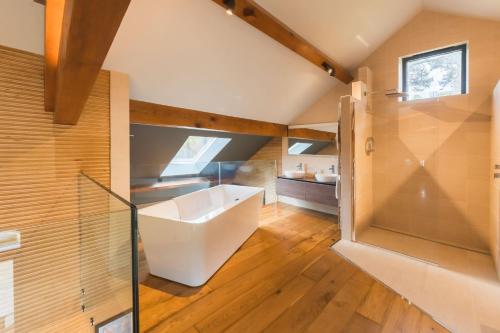 a bathroom with a white tub and a glass wall at Stanage Barn By Birch Stays in Hathersage