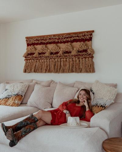 a woman in a red dress laying on a couch at The Raven By The Cohost Company in Pioneertown