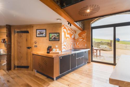 a kitchen with wooden walls and a large window at Stanage Barn By Birch Stays in Hathersage