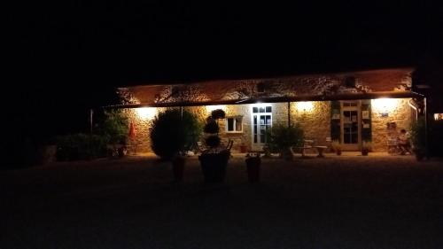 deux personnes debout devant un bâtiment la nuit dans l'établissement Domaine De Gîtes La Ferme Couderc, à Pailloles
