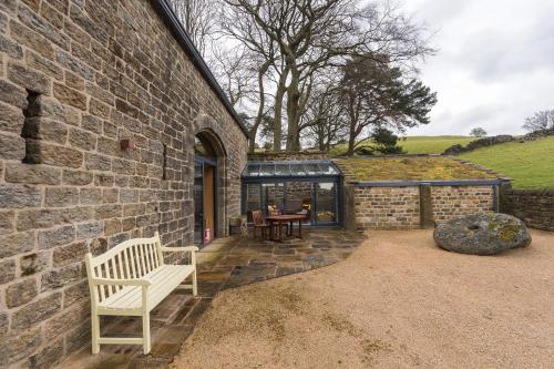 a stone building with a bench and a table at Stanage Barn By Birch Stays in Hathersage