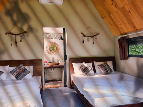 a bedroom with two beds in a room with a mirror at Buon'S garden in Buôn Kao