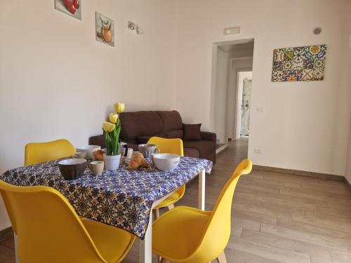 a dining room table with yellow chairs and a table at Il Cavaliere Apartment in Capaci
