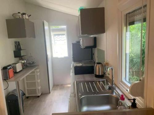 a kitchen with a stainless steel sink and a window at Mobilhome tout confort camping 4 étoiles in La Teste-de-Buch