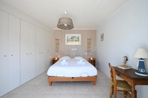 een slaapkamer met een wit bed en een bureau bij Cocon Douillet, plages à 2 pas in La Noue