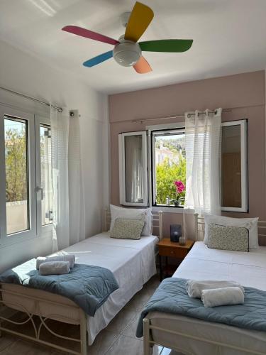 a bedroom with two beds and a ceiling fan at Villa Santa Marina in Spetses
