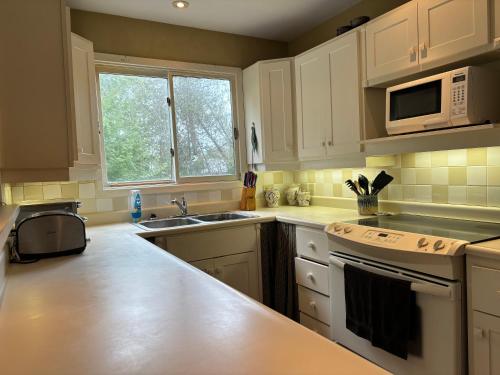 a kitchen with white cabinets and a sink and a microwave at Artistic Haven By The Beach in Wiarton