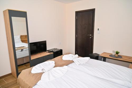 a bedroom with a large white bed with a mirror at Къща Александра 2 in Dobrinishte