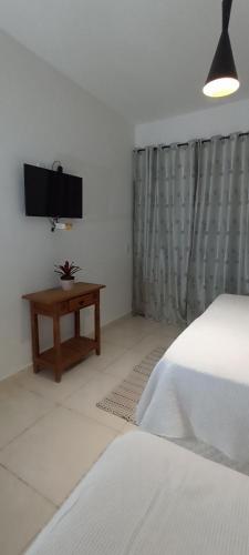 a bedroom with a bed and a tv and a table at Pousada Filhos da Canastra in Vargem Bonita