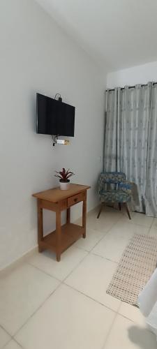 a living room with a tv and a table and a chair at Pousada Filhos da Canastra in Vargem Bonita
