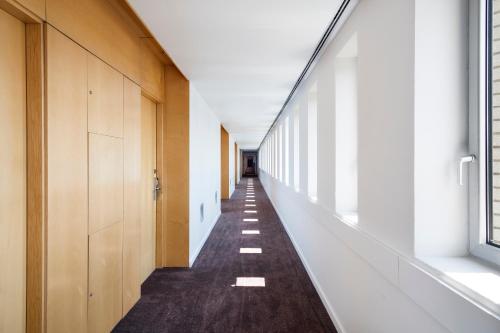 a corridor of a building with white walls and a long hallway at INNSiDE by Meliá Barcelona Aeropuerto in El Prat de Llobregat