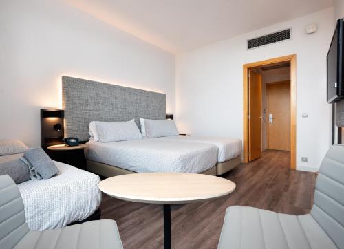 a hotel room with two beds and a table at INNSiDE by Meliá Barcelona Aeropuerto in El Prat de Llobregat