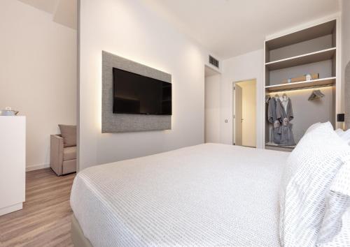 a white bedroom with a bed and a flat screen tv at INNSiDE by Meliá Barcelona Aeropuerto in El Prat de Llobregat
