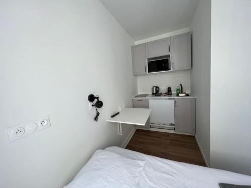 Cette petite chambre blanche dispose d'un lit et d'une cuisine. dans l'établissement Small, Studio Cosy, à Reims