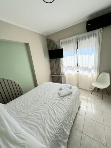 ein Schlafzimmer mit einem weißen Bett und einem Stuhl in der Unterkunft Departamento Exclusivo frente al puerto con cochera in Santa Fe
