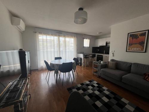 un salon avec un canapé, une table et des chaises dans l'établissement Les Balcons du Soleil - idéal Curistes - classé 3 étoiles, à Saint-Paul-lès-Dax