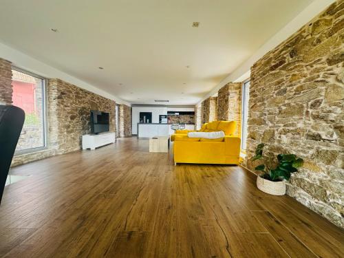a living room with a yellow couch and a stone wall at Casa Suomi in Vigo