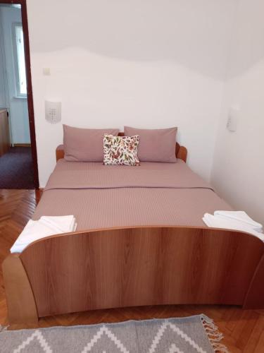 a bed with a wooden headboard in a room at Hotel Vlasina - Vlasinsko jezero in Lujinska Mala