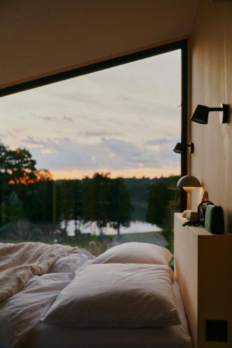 a bedroom with a bed and a large window at Raus Tiny House am See mit Sauna und Whirlpool in Lenzen