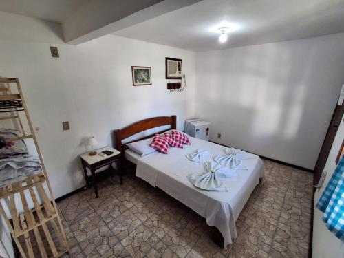 a bedroom with a bed with white sheets and red pillows at Pousada Nova Conquista in Penedo