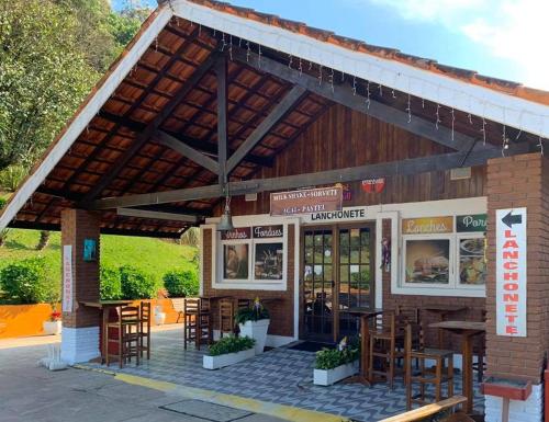 un restaurant avec des tables et des chaises en face de celui-ci dans l'établissement Mirante 45 - O Chalé mais alto do Brasil, localizado a 24km de Campos do Jordão, à Santo Antônio do Pinhal