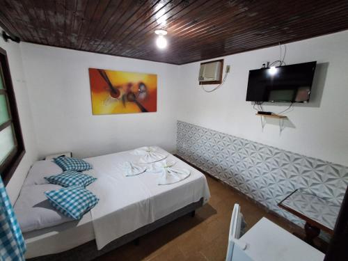 a bedroom with a bed and a flat screen tv at Pousada Nova Conquista in Penedo