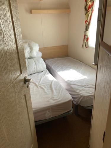 a small room with two beds and a window at Luxury 8 and 6 berth caravans in Jaywick Sands
