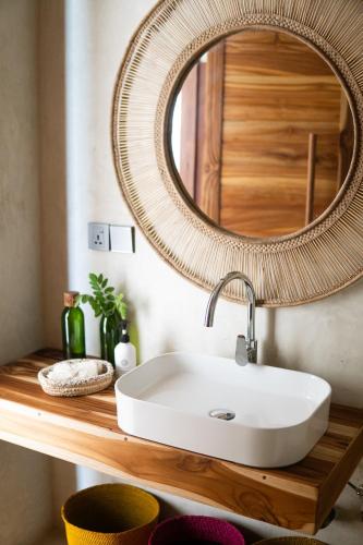 a bathroom with a white sink and a mirror at KUDOS Beach Apartments Jambiani in Jambiani