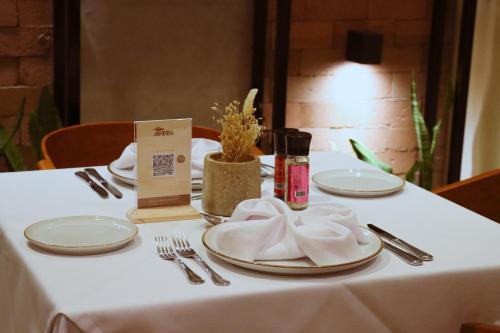a table with white plates and silverware on it at Rado Hotel - Quintanas in Trujillo