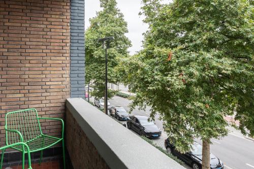 a green bench on a balcony with cars parked on a street at Spacious City Loft With Balcony & High-speed Wi-fi in Tilburg